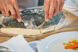 Crop person serving flounder on wooden cutting board