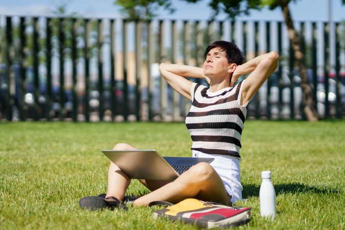 Woman stretching in grassy park while taking a break from work