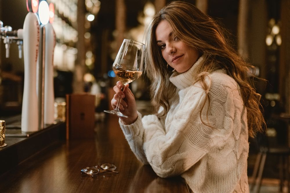 Stylish woman drinking wine in bar