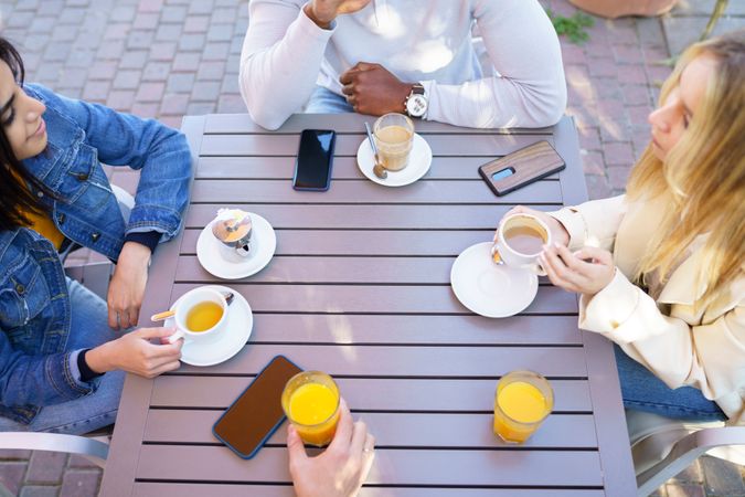 Looking down at multi-ethnic friends with coffee and juice at outdoor table