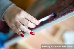 Woman with red nailpolish painting on canvas bGGVlb
