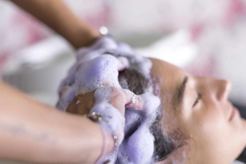 Female lying back having hair washed by hairdresser