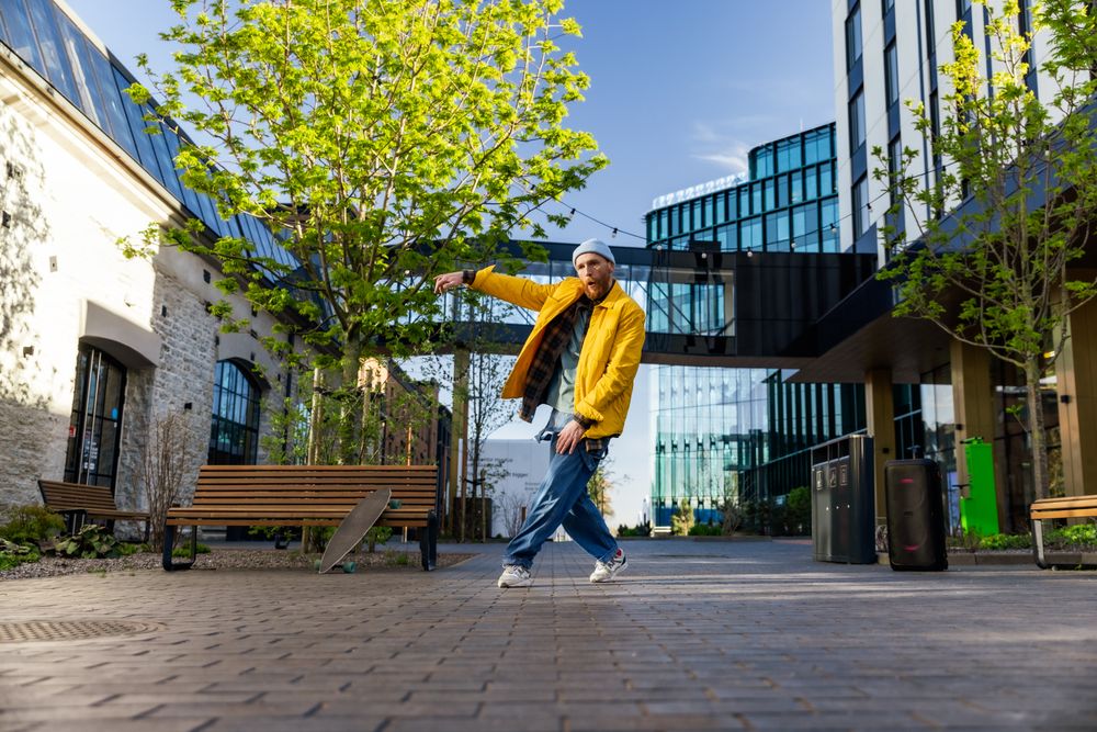 Young And Athletic B-Boy Breakdancing To Break Beats On The City Street Among Modern Buildings Alone With A Speaker.