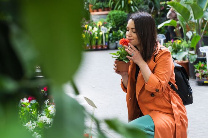 Cheerful woman choosing flowers in garden center