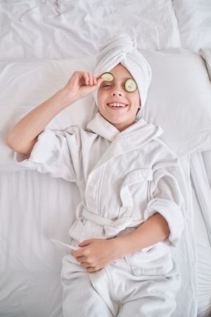 Boy in bathrobe demonstrating cucumber slice