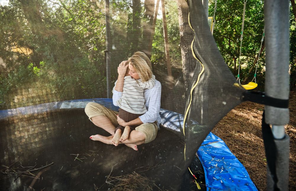 Woman embracing son sitting on trampoline in park