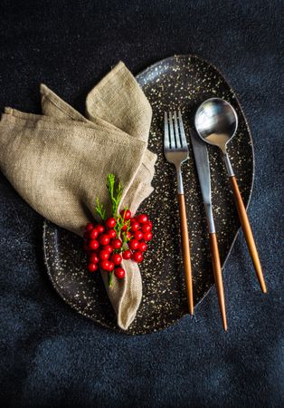 Top view of spotted grey plate and cutlery surrounded by seasonal berries