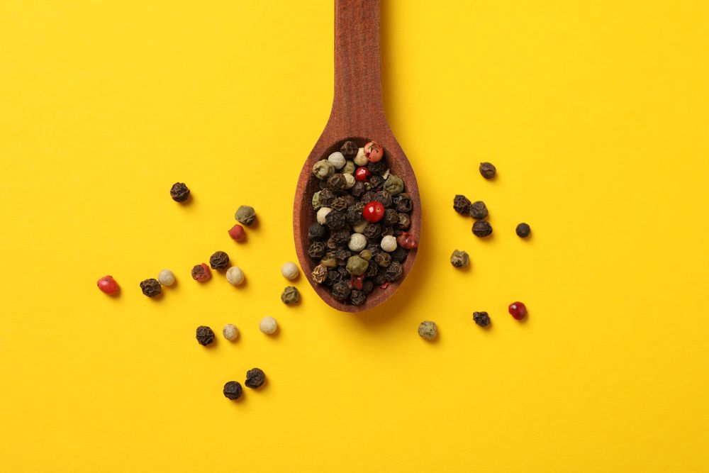 Top view of wooden spoon with whole peppercorns