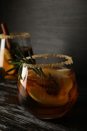 Glasses with apple cider on dark wooden background, close up