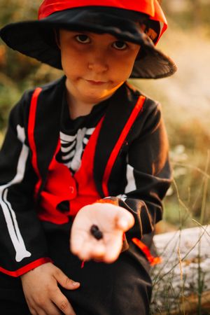 Boy with funny expression in skeleton costume with berries in his hand
