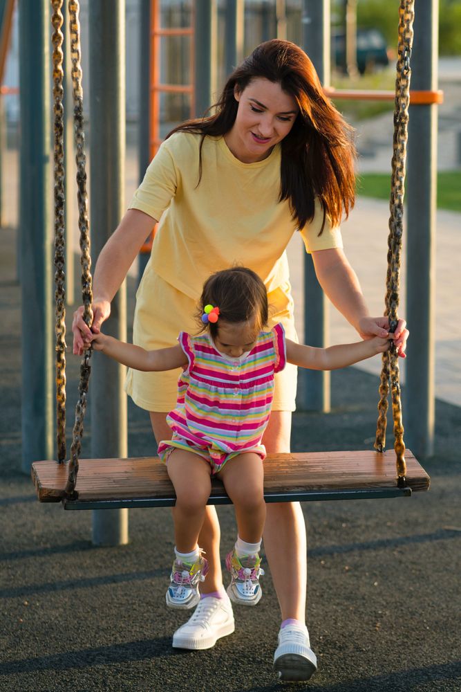 Toddler girl and mom on swing