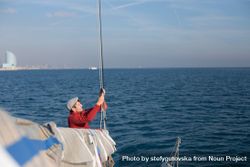 Sailor pulling on cords on sailboat 0KpzZ5