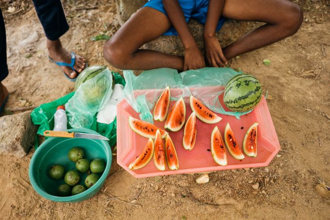 Sri Lankan person at market sitting cross legged in front of freshly cut watermelon