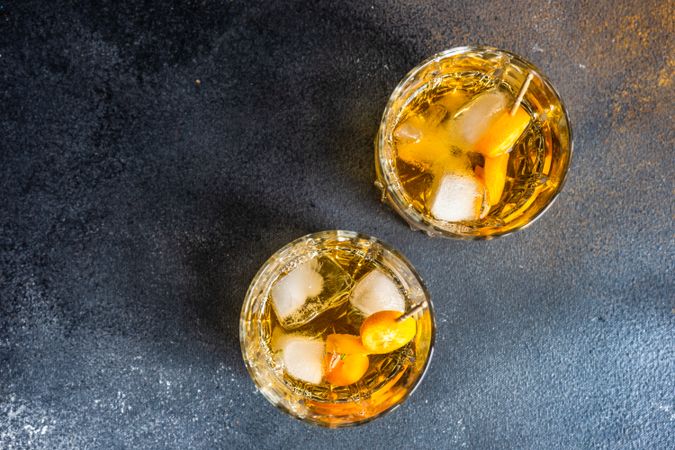 Top view of whiskey on the rocks with slices of kumquat fruit