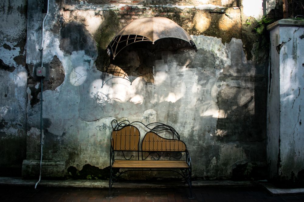 Antique brench on brick wall with  umbrella hanging on wall. Vintage brench park.
