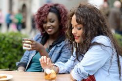 Black female friends having drinks together while sitting outside