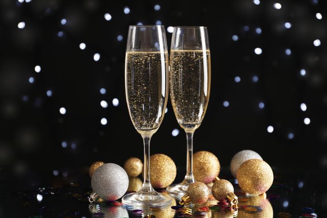 Christmas baubles and champagne glasses on blurred background, copy space