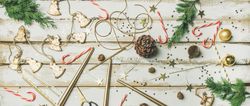 Decorations of stars, candy canes, scissors, candles on light background, wide composition