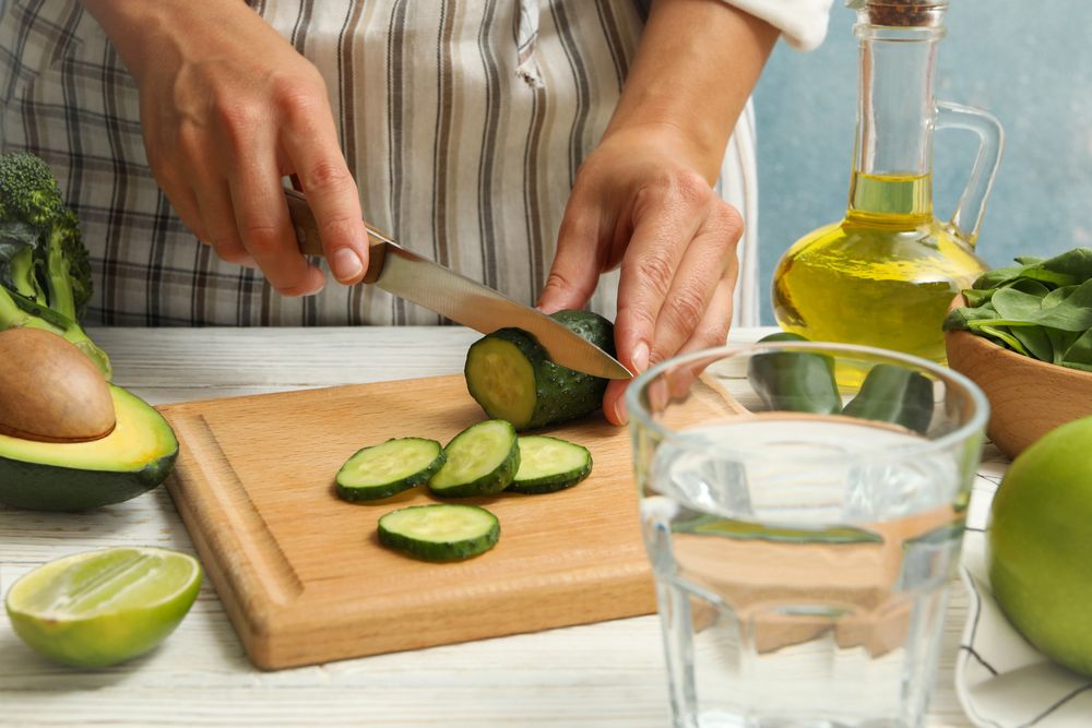 Woman cutted cucumber on wooden table