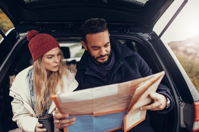 Young couple using a map on a road trip for directions
