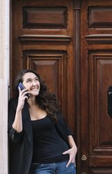 Young female using mobile phone on wooden door