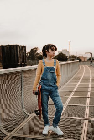 Girl with skateboard on walkway