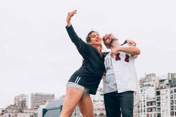 Friends smiling while making selfie on smartphone at city