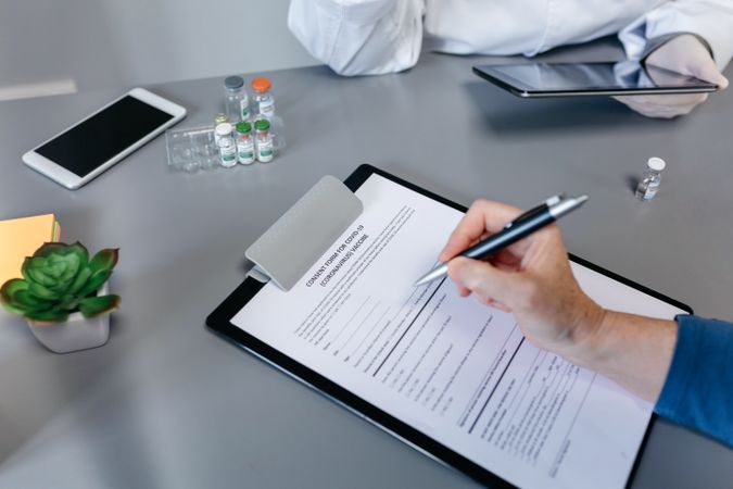 Unrecognizable woman filling in consent form for coronavirus vaccine