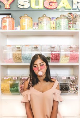Woman with gum in her mouth standing in front of candy stand