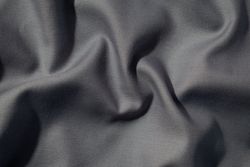 Crumpled wavy dark grey silky fabric background texture. siny and glossy.