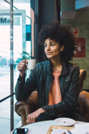 Black woman with afro hair drinking a coffee