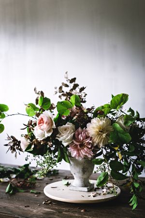 Composition of flowers and plants in vintage vase on board