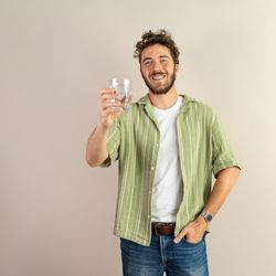 Happy young man holding a glass of fresh water with copy space.