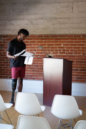 Man with prosthetic leg looking over his notes by a podium