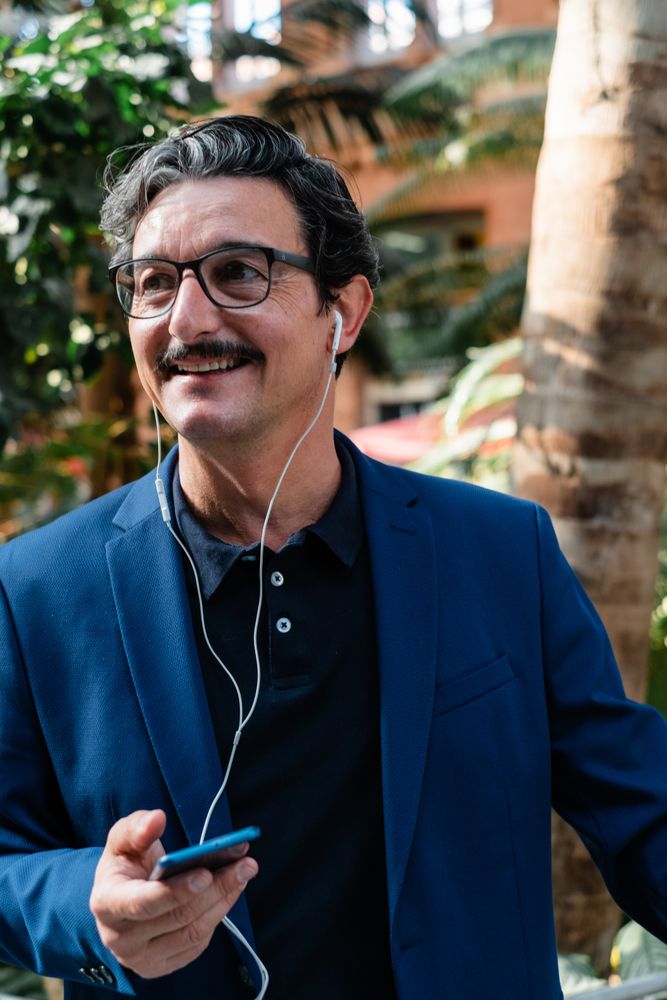 Mature businessman using smartphone with headphones and smiling