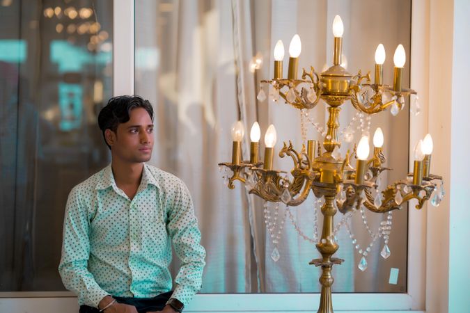 Man in dress shirt sitting beside chandelier