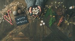 Homely holiday with “Merry Christmas” card, woman and hot chocolate, wide composition, copy space