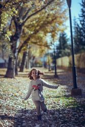 Child running in park of colorful fall leaves