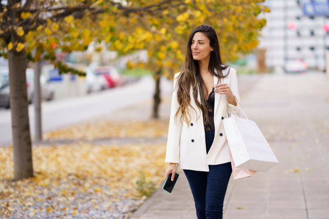 A Stylish Woman Delightfully Enjoys Shopping on an Autumn Day Filled with Colorful Leaves