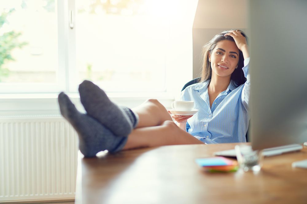 Woman sitting at her desk with feet up and tea cup and saucer