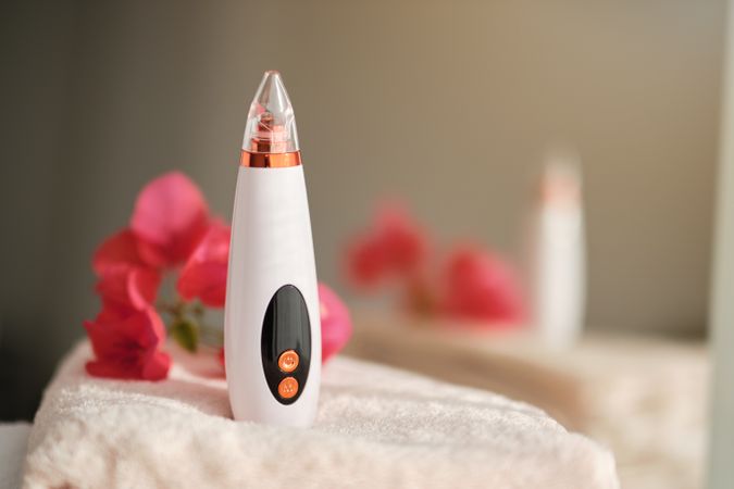 Blackhead remover with flowers on stack of towels