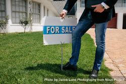Realtor with a for sale sign board outside a house 4mWjed