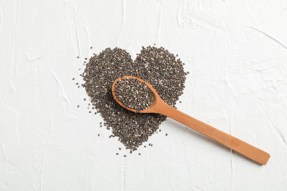 Heart layout of chia and wood spoon on blank background, space for text