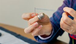 female dressmaker threading a needle