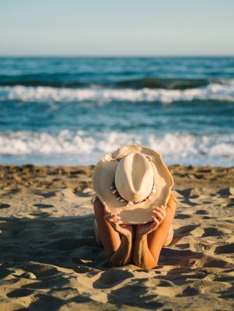 Sandy beach and woman in hat tanning
