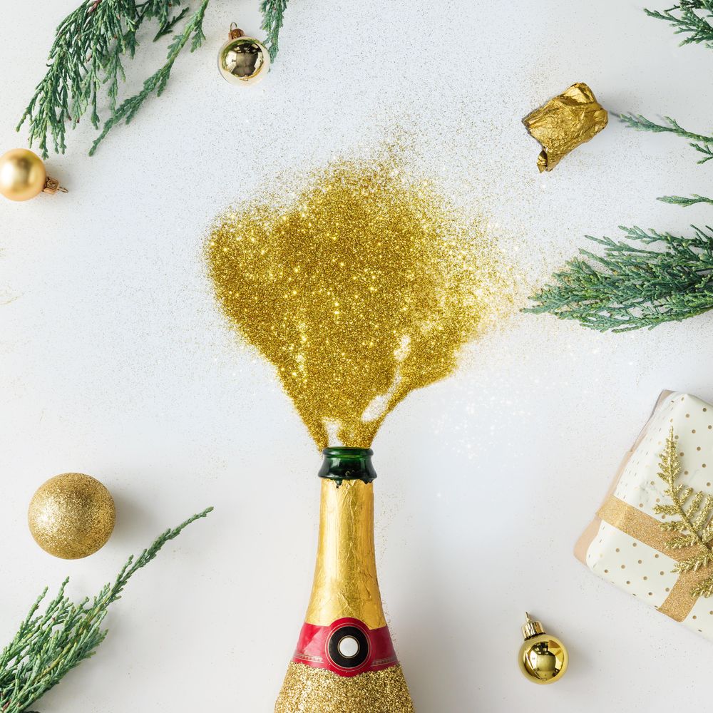 Christmas layout made of Champagne popped with gold glitter pouring out on light background