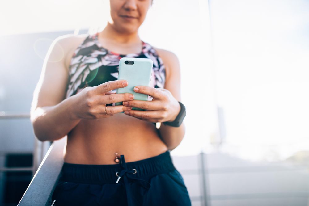 Young woman in sports bra checking mobile phone