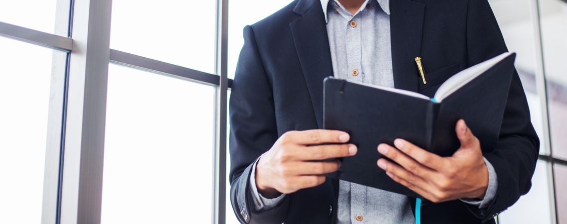 Man in business suit checking notes near office window