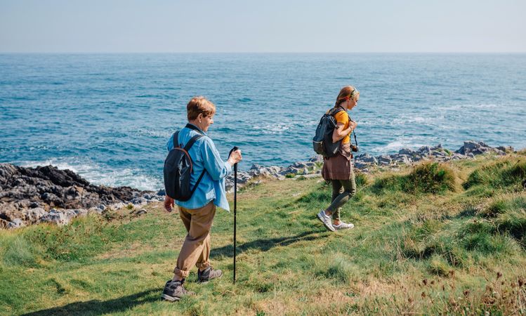 Mother and daughter hiking on beautiful day by the ocean