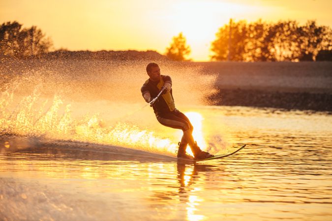 Man wakeboarding on a lake with sunset in the background